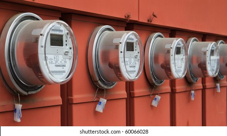 Line up of five electric power meters on red electrical panels