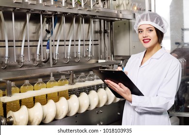 line of food production of refined sunflower oil. Girl worker at a factory on a conveyor background with bottles of vegetable oil. - Powered by Shutterstock