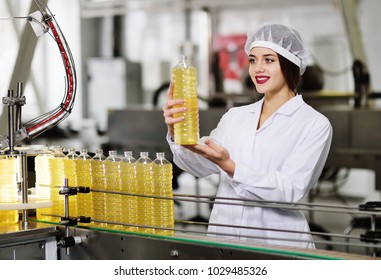 line of food production of refined sunflower oil. Girl worker at a factory on a conveyor background with bottles of vegetable oil.