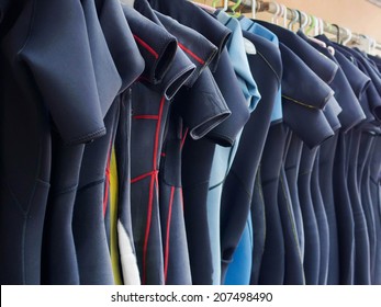 Line of multiple hanging wetsuits at scuba diving center.