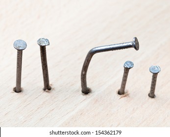 line of nails and curved nail in wooden board