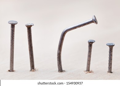 line of nails and curved nail in wooden plank