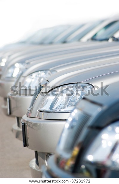 Line of new compact\
cars at a dealer lot.