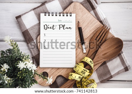 Line Notepad with Diet Plan list text  on chopping board with wooden fork and spoon and measuring tape on white table , recipes food or diet plan for healthy habits shot note background concept