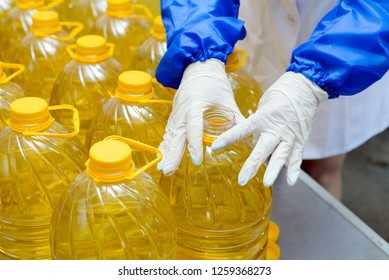 line of production of refined sunflower oil. Girl worker at a factory on a conveyor background with bottles of vegetable oil.
