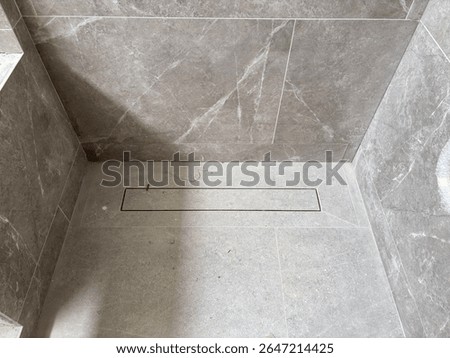 linear shower drain on tiled floor of modern enclosure in luxury bathroom, water disposal system, detail in loft washroom interior, minimalistic style