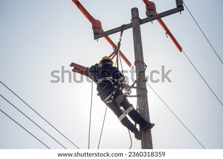 Lineman electrician engineer working climbing a pole to repair and maintain a power line and a transformer