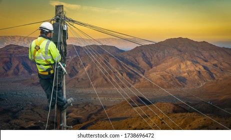 Lineman (Or Lineworker Or Engineer) In A Remote Desert Landscape Fixing A Telephone Line