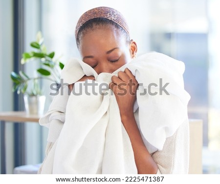 Linen, cleaning and fresh with a black woman smelling fabric or textile while working in a home as a cleaner. Laundry, housekeeping and scent with a female maid at work with soft sheets to smell