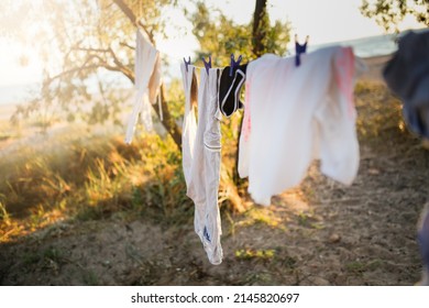 Linen Clothes Are Dried On A Rope Among Trees, Sand And Beach And Clothesline