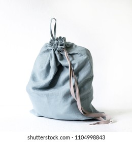 Linen Drawstring Bag Full Of Laundry On White Background.