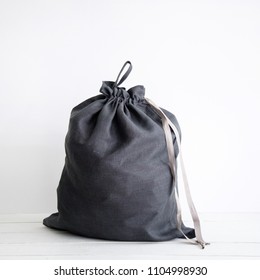 Linen Drawstring Bag Full Of Laundry On White Background.