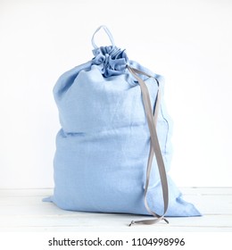 Linen drawstring bag full of laundry on white background.