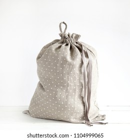 Linen Drawstring Bag Full Of Laundry On White Background.