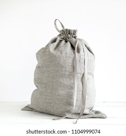 Linen Drawstring Bag Full Of Laundry On White Background.