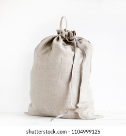 Linen Drawstring Bag Full Of Laundry On White Background.