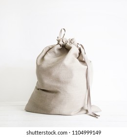 Linen Drawstring Bag Full Of Laundry On White Background.