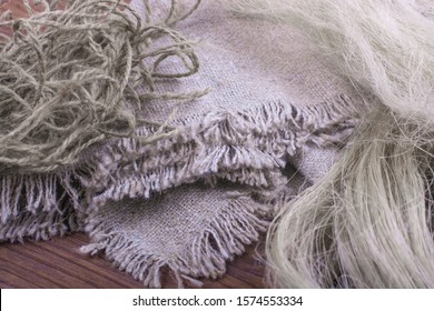 Linen fabric and flax threads on a wooden table close-up.