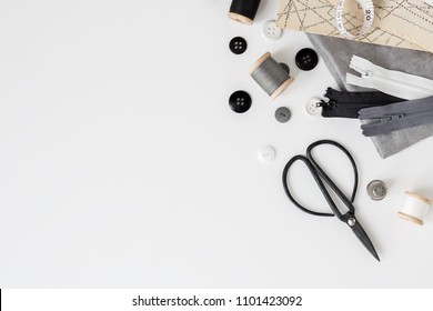 Linen textiles, scissors and sewing supplies on white desk