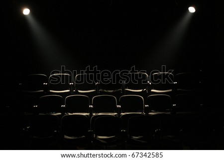 lines of theater chairs in darkness with two reflectors
