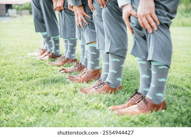 A lineup of groomsmen wearing gray suits and fun mustache socks, showcasing personality and humor at a wedding. - Powered by Shutterstock