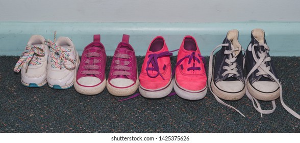 Lineup Of Kids Shoes On A Blue Dirty Wall 