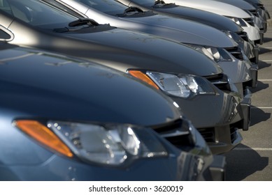 A Lineup Of New Cars At A Dealership. (Shot With Minimum Depth Of Field. Focus Is On The Third Vehicle From The Front.)