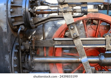 A linkage of an old steam locomotive with a red wheel in close-up