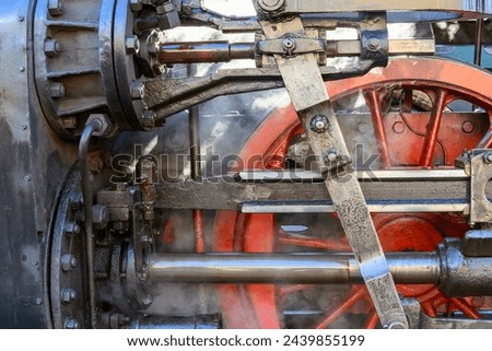 A linkage of an old steam locomotive with a red wheel in close-up