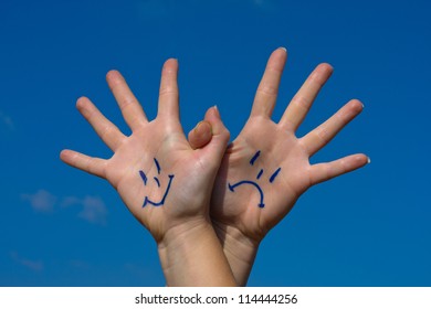 Linked hands with smiles and sadness pattern against the blue sky