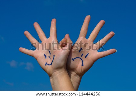 Linked hands with smiles and sadness pattern against the blue sky