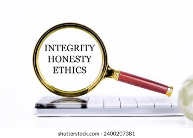 lINTEGRITY HONESTY ETHICS ettering through a magnifying glass on a calculator and part of a magic ball in the foreground without focus