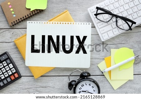 LINUX . light wooden background yellow notepad with torn page with text near desk clock calculator