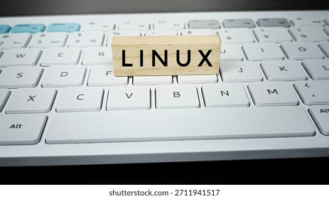 Linux operating system concept with wooden block on computer keyboard, illustrating open source software, technology, IT solutions, programming, and digital computing. 