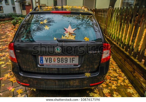 LINZ, AUSTRIA -\
NOVEMBER 13, 2017: autumn leaf on back window car. rainy day. rain\
drop glass. autumn time season\
