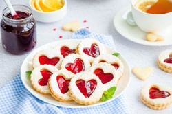 Linzer Cookies With Heart With Raspberry Jam And Powdered Sugar On A White Plate With A Cup Of Tea. Dessert On Valentine's Day. Horizontal Orientation.