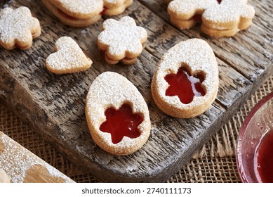Linzer cookies in the shape of Easter eggs filled with red strawberry marmalade and dusted with sugar, closeup