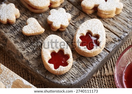 Linzer cookies in the shape of Easter eggs filled with red strawberry marmalade and dusted with sugar, closeup