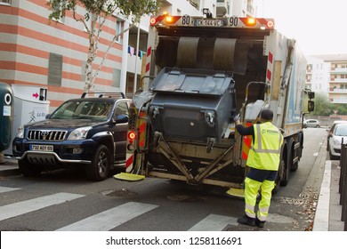 Lion, France - 14.10.2017: Two Refuse Collection Workers Loading Garbage Into Waste Truck Emptying Containers