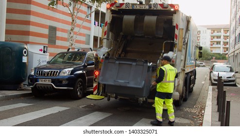 Lion, France - 14.10.2017: Two Refuse Collection Workers Loading Garbage Into Waste Truck Emptying Containers