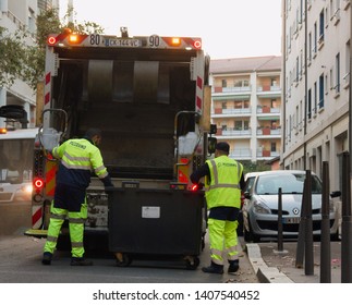 Lion, France - 14.10.2017: Two Refuse Collection Workers Loading Garbage Into Waste Truck Emptying Containers