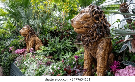 Lion statues amidst lush tropical plants and vibrant flowers inside the Biltmore Conservatory, showcasing an exotic and artistic indoor garden display. - Powered by Shutterstock