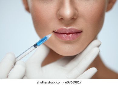Lip Augmentation. Beautiful Young Woman's Mouth Receiving Hyaluronic Acid Injection. Closeup Of Beautician Hands Doing Beauty Procedure To Sexy Female Lips. Cosmetology Treatment. High Resolution