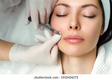 Lip augmentation and correction procedure in a cosmetology salon. The specialist makes an injection in the patient's lips
