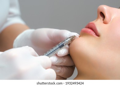 Lip augmentation and correction procedure in a cosmetology salon. The specialist makes an injection in the patient's lips - Powered by Shutterstock