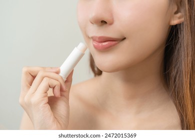 Lip care protection concept, pretty asian young woman, girl hand applying lipstick balm with moisturising on dry mouth from natural beauty product, skincare routine, makeup and cosmetics on background