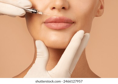 Lip injections concept. Young lady getting beauty injection in her lips, beautician holding syringe with filler next to woman mouth, cropped