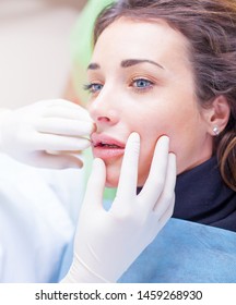 Lip massage after receiving a botox injection in woman lips. Doctor's hands in white gloves touch the lips, plastic surgery, contour lip surgery, hyaluronic acid.
