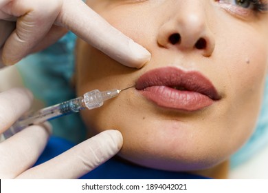 Lips augmentation injections for attractive girl. Plastic surgeon does injection in lip in medical clinic. Cosmetic rejuvenating facial treatment. Empty space for advert