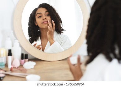 Lips Care. Beautiful Black Woman Applying Moisturising Balsam, Reflecting In Mirror In Bathroom, Selective Focus